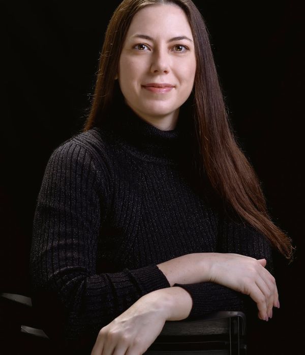 Woman holding a serene yoga pose in a dark, minimalist studio.